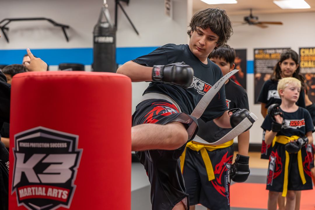 Teen throwing a knee strike on a red bag during class at K3 Martial Arts in Roseville, California