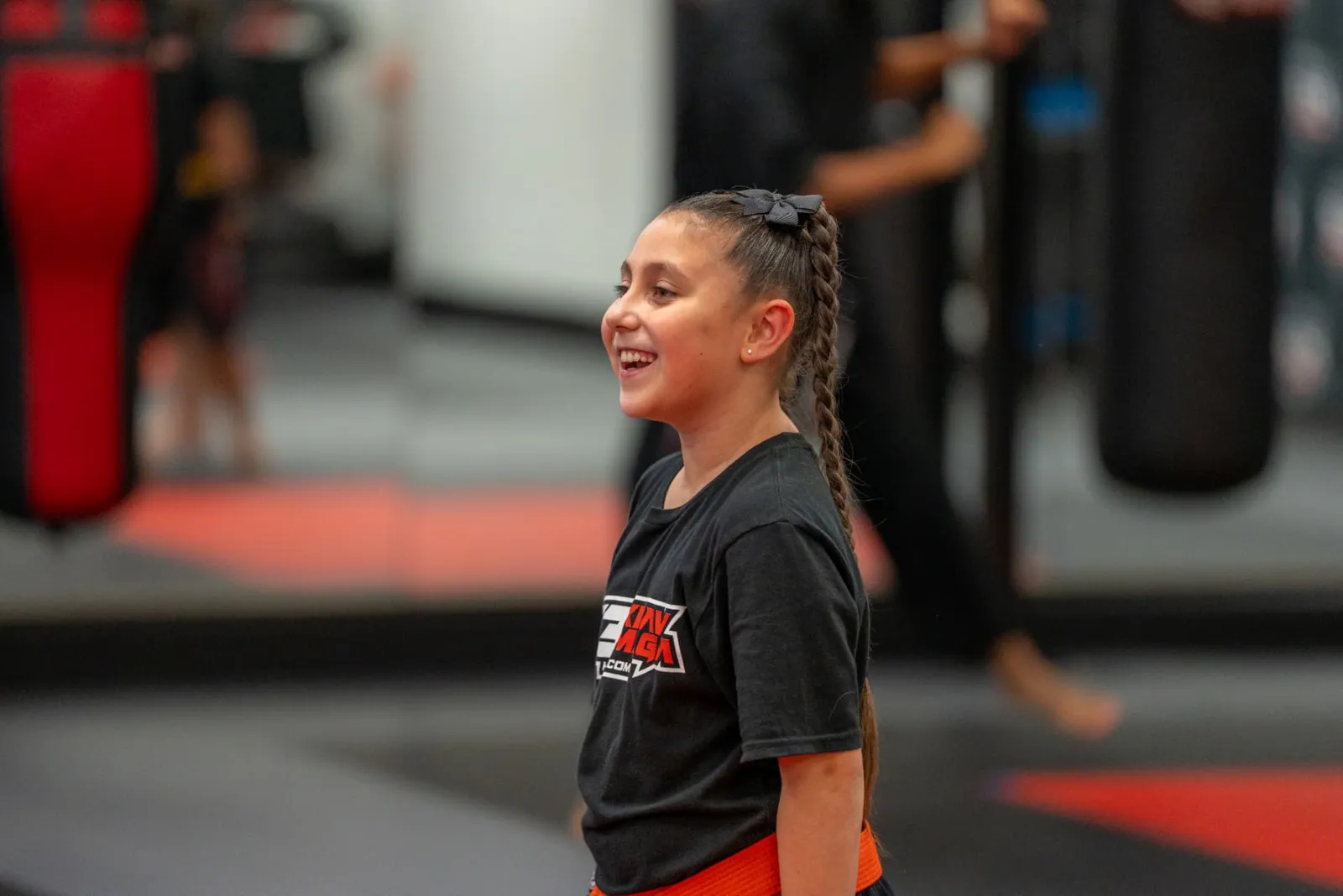 Smiling girl with an orange belt on the mat